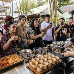 A chef demonstrating a dish to a group of visitors outdoors