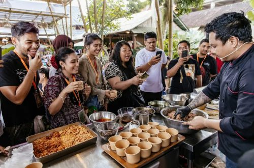 A chef demonstrating a dish to a group of visitors outdoors