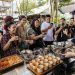 A chef demonstrating a dish to a group of visitors outdoors