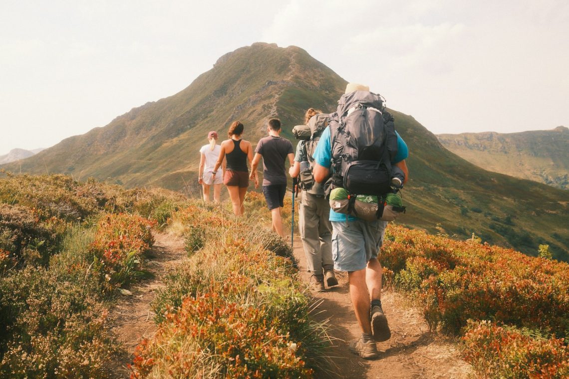 A group of hikers on a trail heading toward a mountain peak