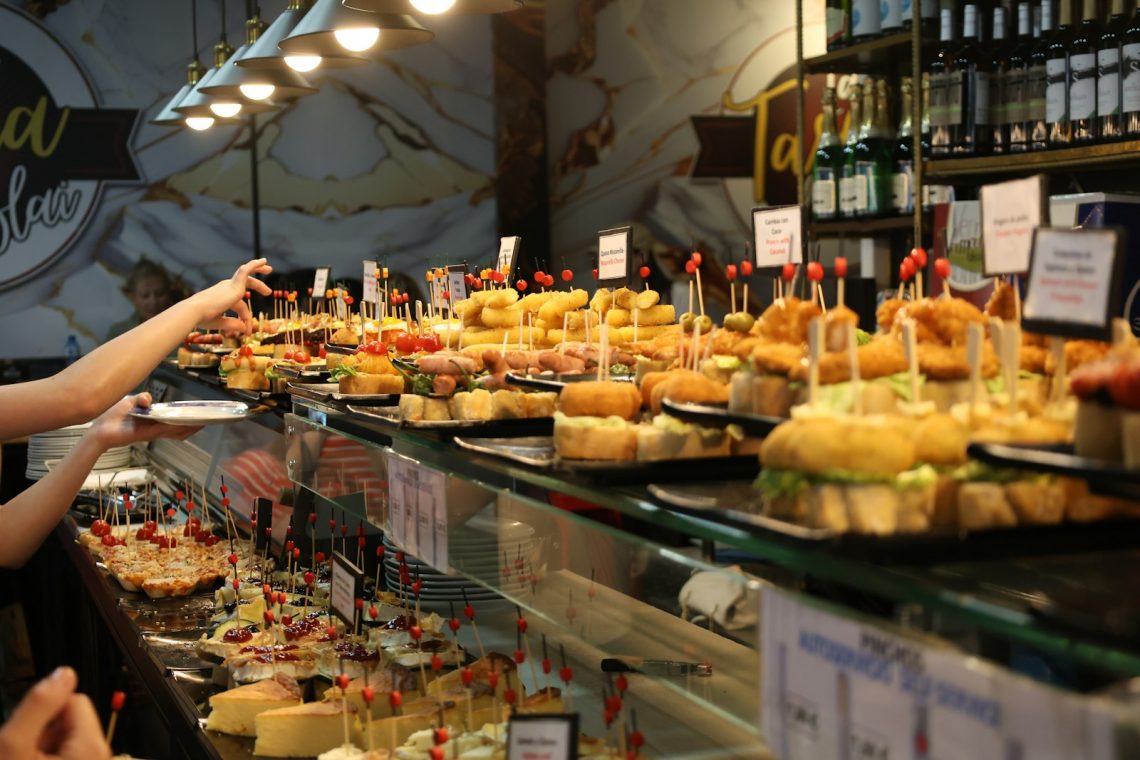 A bar counter lined with small plates of pintxos
