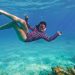 A snorkeler swimming in clear blue water above coral