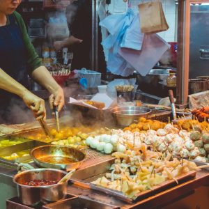 A vendor cooking skewers at a street food stall