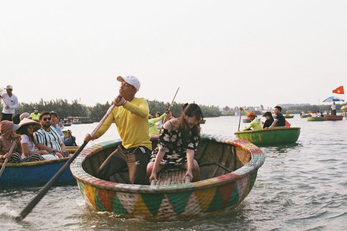 A boatman rowing visitors in a round basket boat on a river