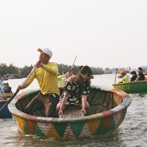 A boatman rowing visitors in a round basket boat on a river