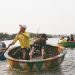 A boatman rowing visitors in a round basket boat on a river